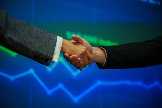 Business professionals shaking hands after reaching an agreement at a seminar, representing partnership, successful negotiation, collaboration, trust, networking and corporate growth.