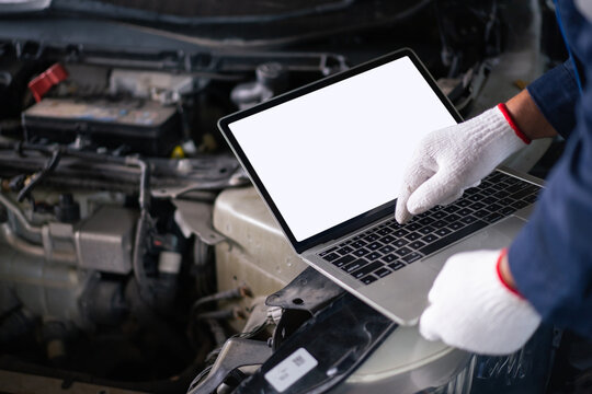 Male mechanic connecting laptop to car engine system for diagnostic test