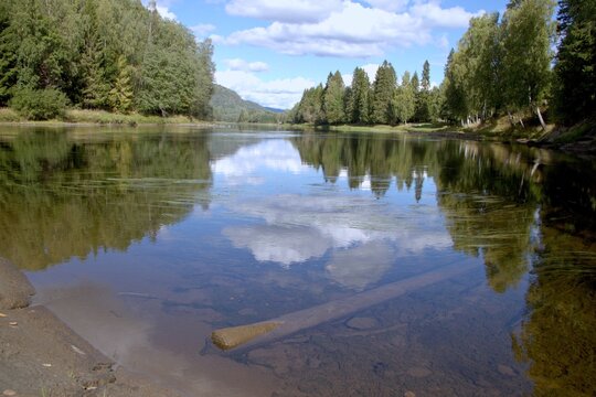 Numedalsl&aring;gen river with reflections of forest and clouds in Norway