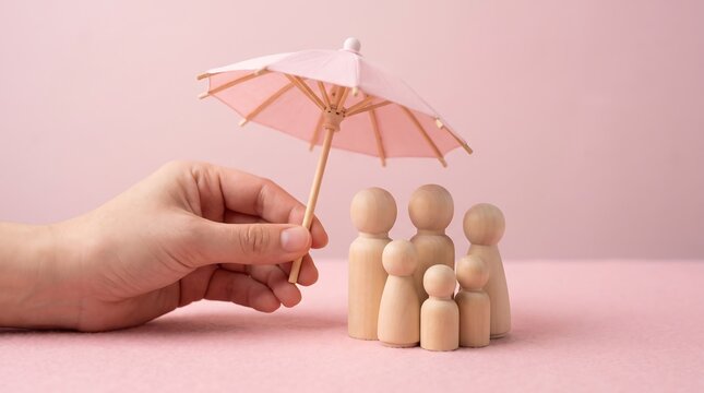 Family life insurance concept, wooden peg figures under pink umbrella, hand protecting family with insurance coverage
