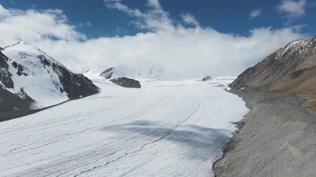 Sweeping camera movement revealing the vast Potanin Glacier surrounded by snow-covered peaks in the Altai Tavan Bogd Mountains of western Mongolia, showcasing the remote and dramatic high-altitude lan