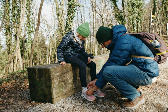 EDITOR'S NOTE: IMAGE IS NOT IN FOCUS Man tying a young girl's shoe on a woodland trail.