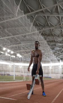 Black athlete with starting block in stadium