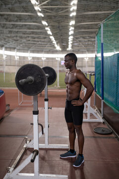 Black sportsman preparing to exercise with barbell