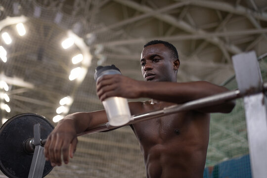 Exhausted black weightlifter with water resting