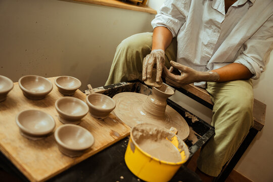 Potter Shaping Clay on a Wheel While Creating Bowls Indoors