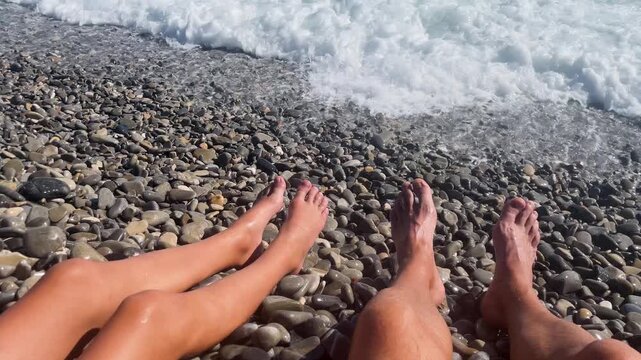 Child and dad legs is overwhelmed by a wave. Pebble sea of the Mediterranean Sea near Nice, Cote d'Azur, southern France