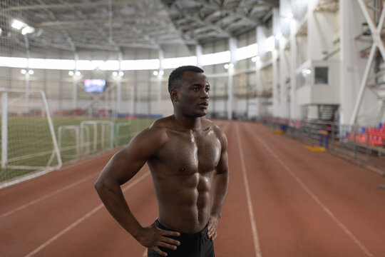 Muscular black runner resting on track