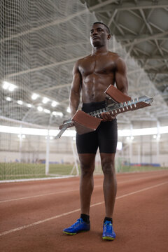 African American sportsman carrying starting block