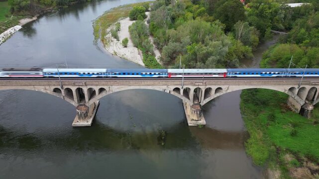 Milan &ndash; Pavia &ndash; Genoa railway line: drone view of a regional train and an Intercity train crossing the bridge over the Ticino River in Pavia, Italian Railways and the modernization of the rail network