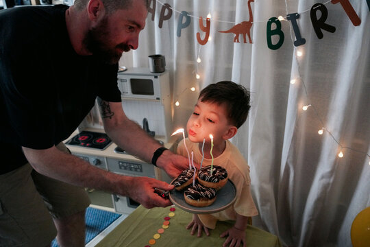 A Little Boy Blows Out The Candles On His Birthday At Home