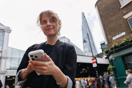 Woman using smartphone in London with The Shard