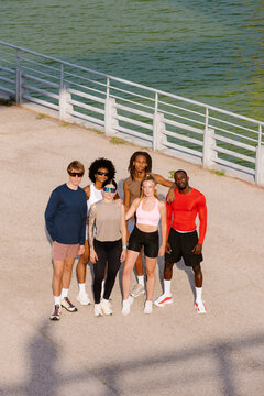 Morning runners posing with empowered attitude by a lakeside sunrise.