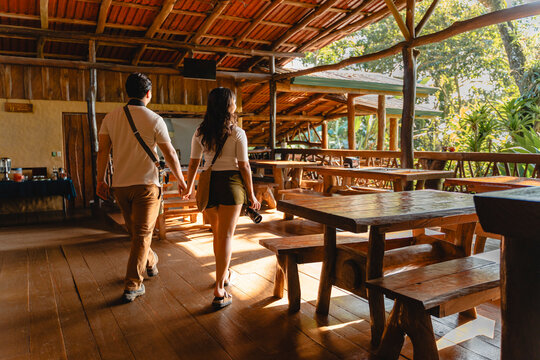 Couple holding hands walking through rustic lodge restaurant