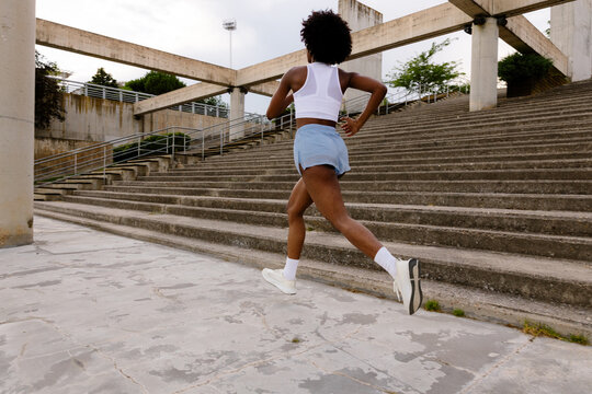 Wide shot of a female runner jogging in a park during morning training
