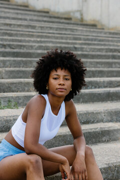 Medium portrait of a confident athletic woman on park stairs.