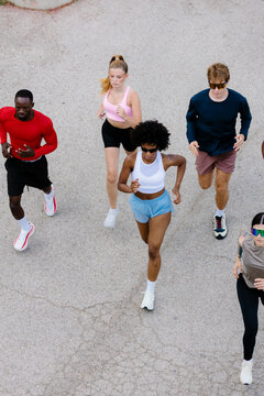 Bird's-eye view of diverse fitness enthusiasts running outdoors.