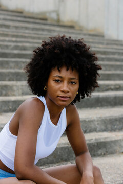 Medium shot of a female athlete leaning on knees on park stairs
