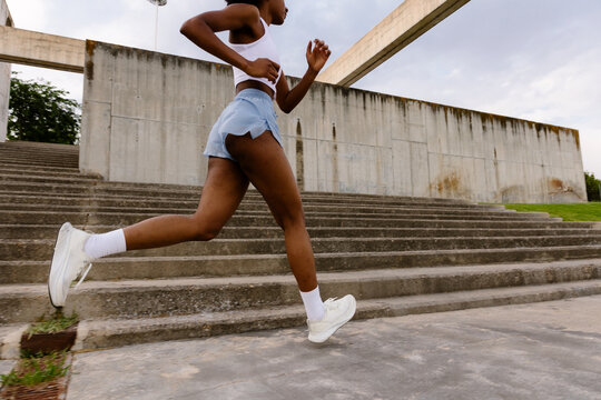 Full-body shot of a fit woman running in a park on a sunny morning