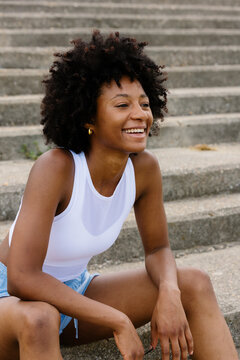 Medium shot of a cheerful female runner sitting on park stairs.