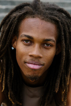 Close-up of a smiling Black man with dreadlocks looking at camera.