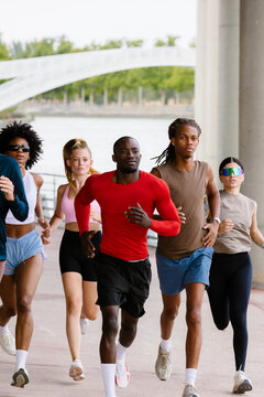 Full-body shot of a group of friends running together in a park.