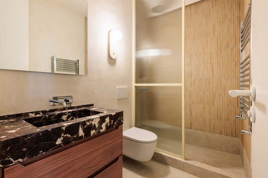 Dark marble vanity near glass shower
