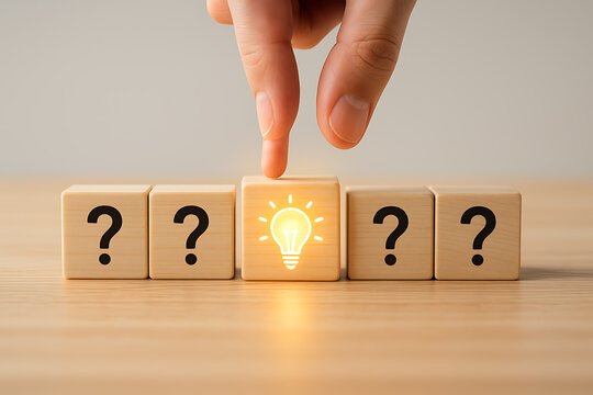 Wooden cubes with question marks and a glowing lightbulb a conceptual photograph