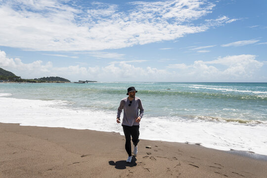 Man Walking Along Sunny Ocean Beach