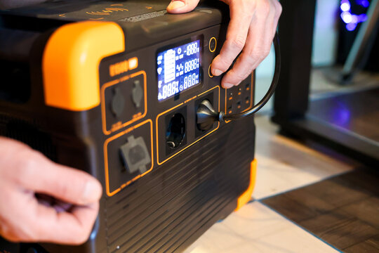 Close up portable power station. A mans hand is connecting a charging power station for work. Altrnative energy for blackout times. 