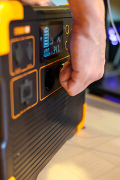 Close up portable power station. A mans hand is connecting a charging power station for work. Altrnative energy for blackout times. 