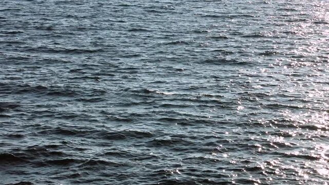 Sunlight Shimmering on Moving Ocean Water Surface. Small ocean waves moving across the sea surface with sunlight shimmering and reflecting on the water.