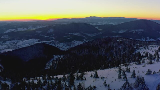 An extraordinary valley with hills and mountains covered with fir forests against the backdrop of a bright fiery sunset