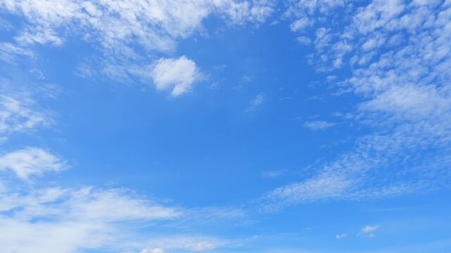 A blue sky cloud timelapse video featuring scattered cirrocumulus and altocumulus clouds drifting through bright daylight, revealing atmospheric motion, gentle weather changes, and serene nature.
