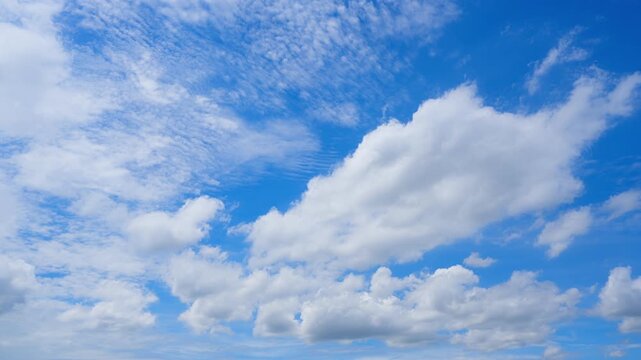 A blue sky cloud timelapse video showing towering cumulus and textured altocumulus clouds moving across a vivid sunlit sky, capturing dynamic airflow, changing weather, and bright daytime atmosphere.
