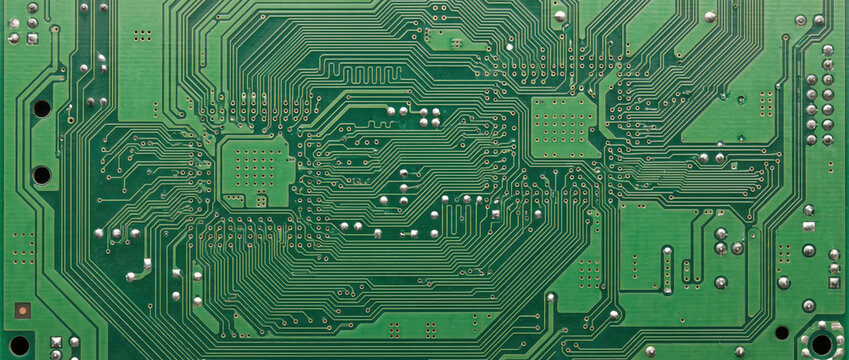 Green printed circuit board texture. Macro overhead view of complex computer motherboard with copper pathways and solder joints. Technology background
