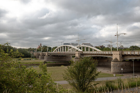 Poznan, Poland - July 8, 2026: White steel arches of Saint Roch Bridge span the Warta River, partially framed by trees along the riverfront.