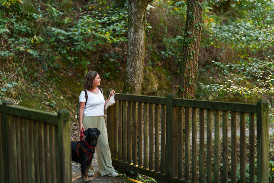 Woman walking with her black dog in an autumn forest