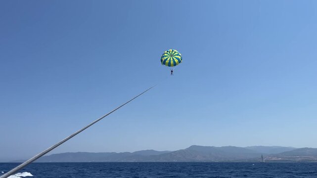 Two people parasailing in the blue sky over the sea, view from the boat