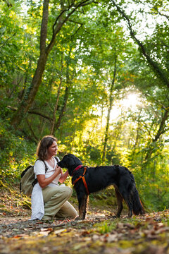 Woman walking with her black dog in an autumn forest