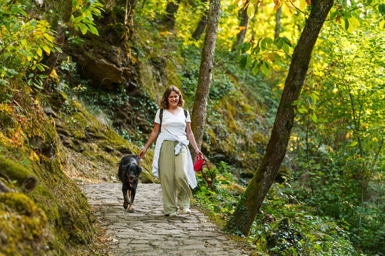 Woman walking with her black dog in an autumn forest