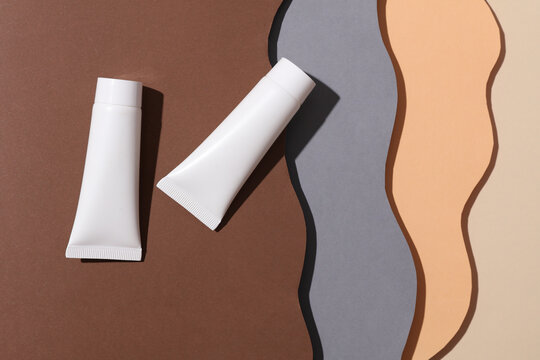 White cream tubes on cut paper background of wavy layers. Creative layout. Beauty concept. Minimalism