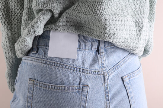 Close-up rear view of slim woman in blue jeans with white blank tag