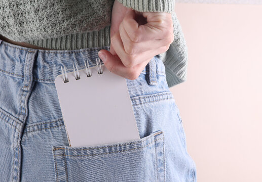 Blank white notebook in back pocket of blue jeans on a woman