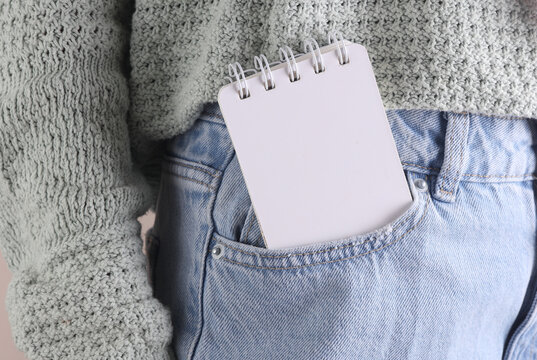 Blank white notebook in front pocket of blue jeans on a woman