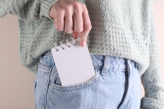 Blank white notebook in front pocket of blue jeans on a woman