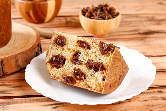Slice of chocolate panettone in a festive arrangement on a rustic table set for a Christmas celebration.