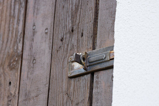 Close-up of an old rusty bolt latch on a weathered wooden door