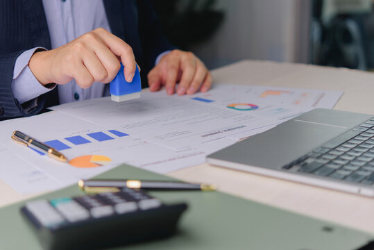 Document Approval with Stamp Laptop and Financial Reports for Business Authorization Administrative Review and Office Paperwork Processing