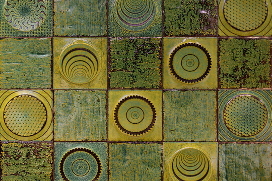 Textured Green Ceramic Tiles with Circular Geometric Motifs. Decorative green and yellow ceramic tiles with textured glaze and repeating circular geometric motifs.